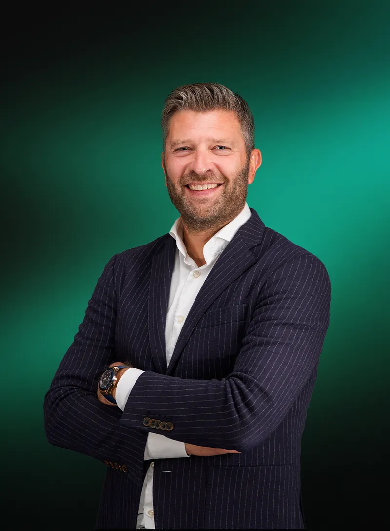 Lachend portret van Eelco Hutten met de armen over elkaar, tegen een groene achtergrond