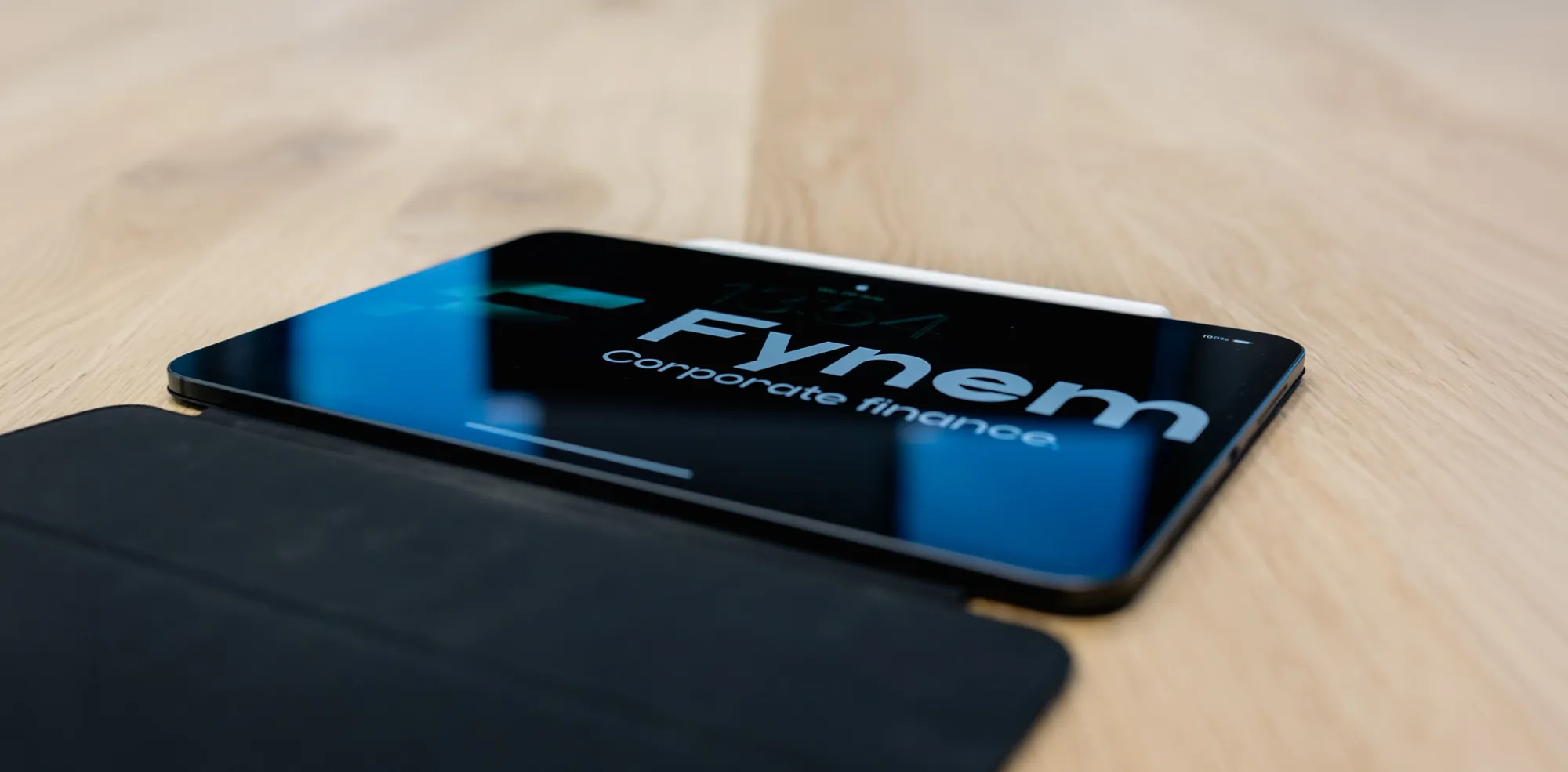 Tablet met het logo van Fynem Corporate Finance op een houten tafel